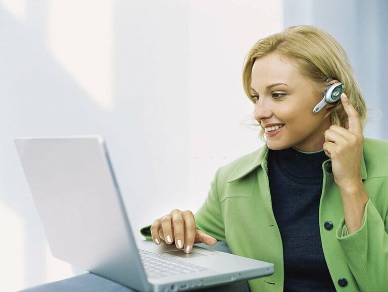 Low angle view of a businesswoman wearing a headset and working on a laptop