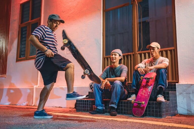 Young Romanian man shows off his skateboarding skills in front of his Asian friends sitting in the back alley at night