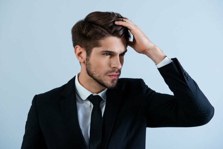 Portrait of handsome young man in black suit brushing his hair