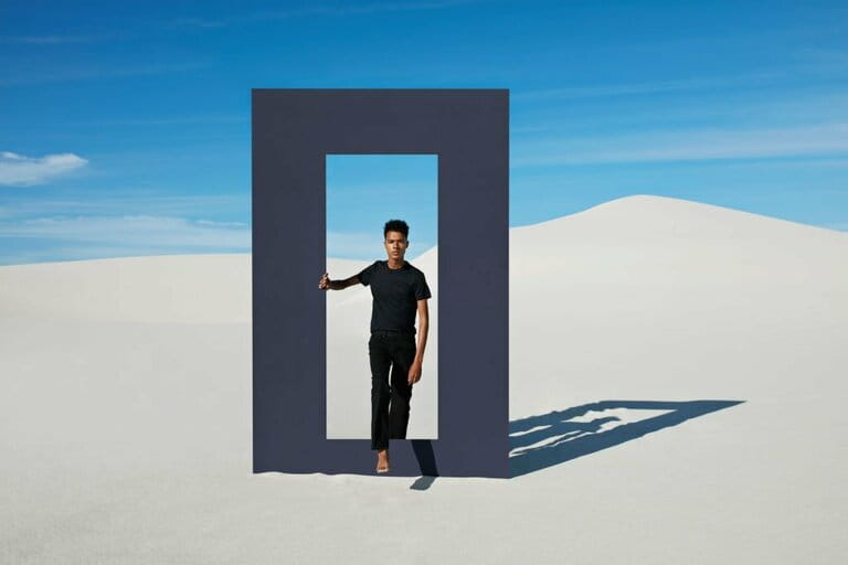 Portrait of young man walking through door frame at desert
