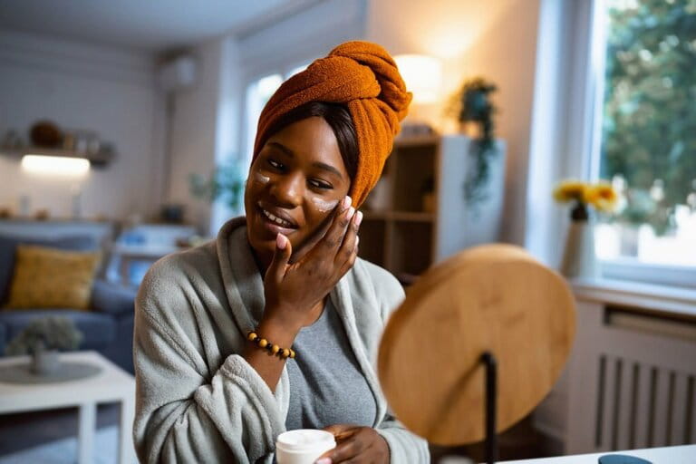Young woman of black ethnicity, applying face cream