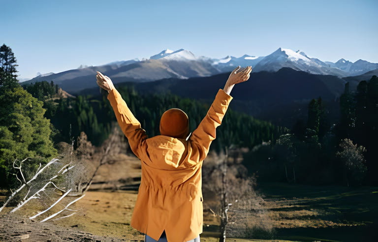 Man full-length hiker standing with her back raised hands up on the mountain 