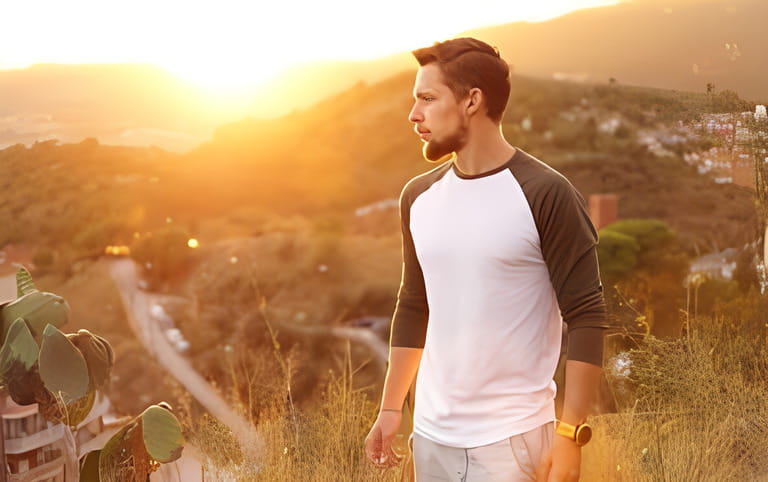 Young attractive man in reglan shirt with long sleeves standing on a hills with nice city view Young attractive man in reglan shirt with long sleeves standing on a hills with nice city view