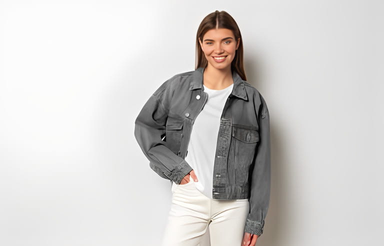 Fashionable trendy girl in casual outfit, gray jean jacket and white pants posing against blank studio wall with copy space for your promotional content. Beauty and fashion concept