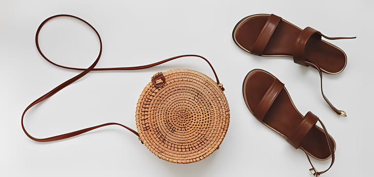 Top view of stylish female sandals and a wicker rattan bag isolated on white background.