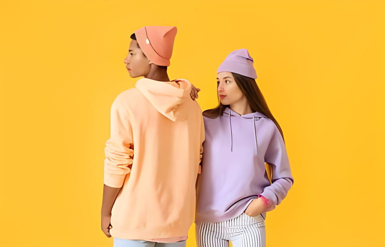 Stylish young couple in hoodies on yellow background Stylish young couple in hoodies on yellow background