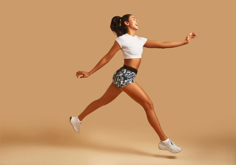 Sporty young woman in sportswear running in front of brown background Sporty young woman in sportswear running in front of brown background