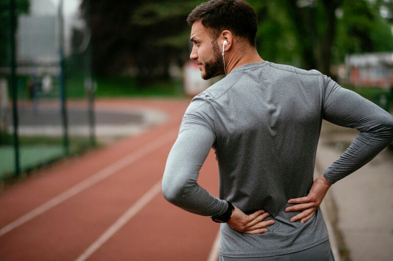 Sportsman suffering from backache at park outdoors Sportsman suffering from backache at park outdoors