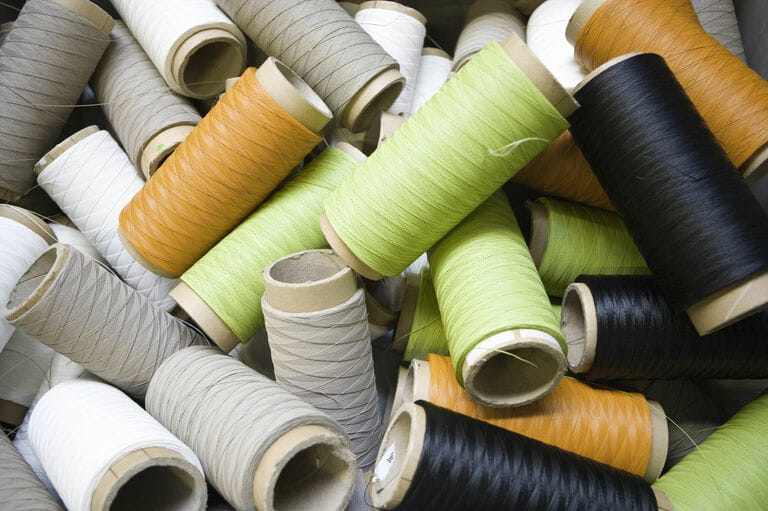 Recyclable composite textile fabrication department of factory, reels of excess coated thread