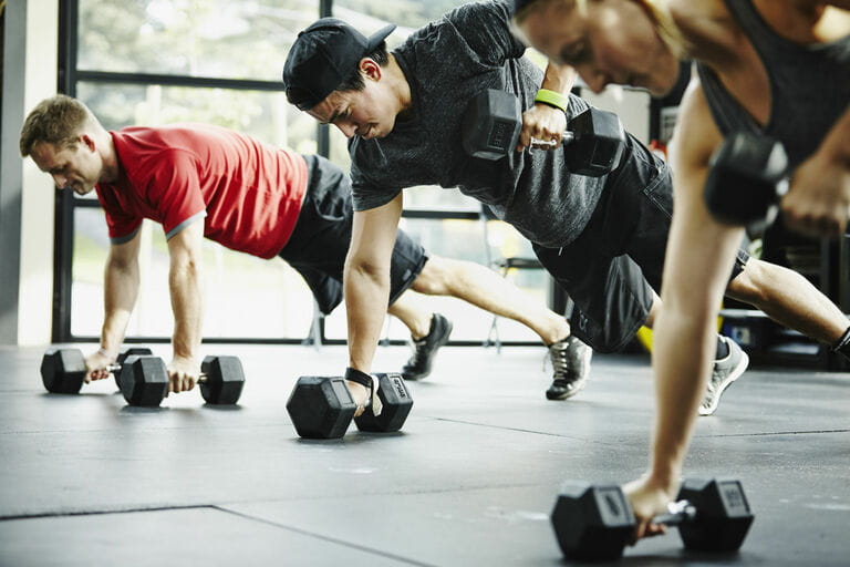 Group of friends doing pushups with dumbbells Group of friends doing pushups with dumbbells