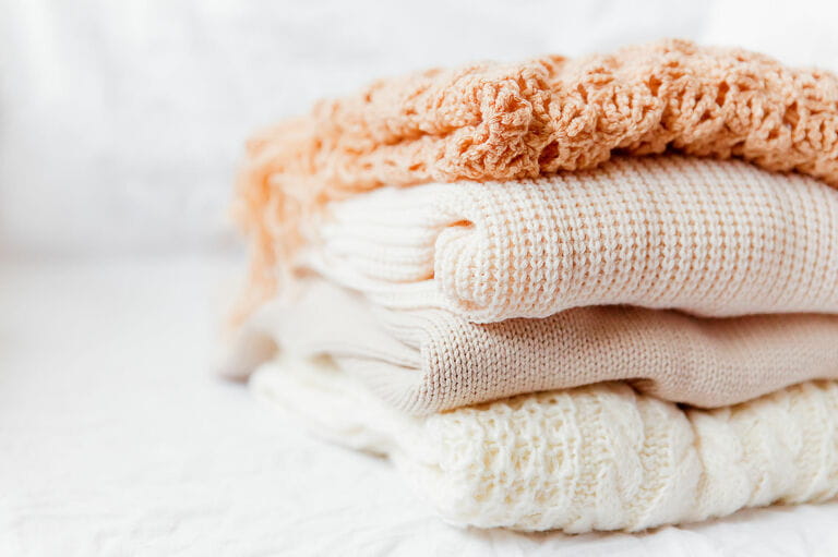 Pile of beige woolen clothes on white background Pile of beige woolen clothes on white background