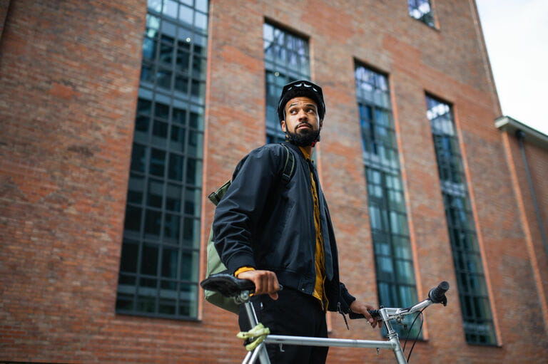 Low angle view of man commuter with bicycle walking in city, sustainable lifestyle Low angle view of man commuter with bicycle walking in city, sustainable lifestyle