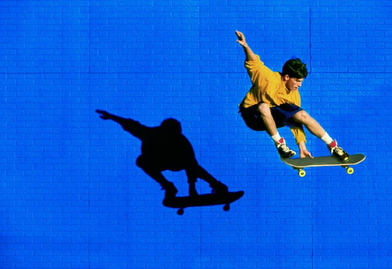 Skateboarder Flying Past Blue Brick Wall Skateboarder Flying Past Blue Brick Wall