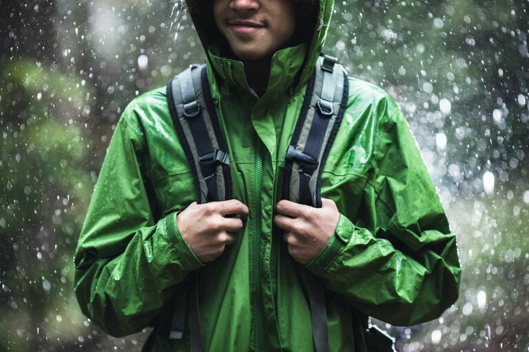 Young man hiking in the rain with waterproof jacket