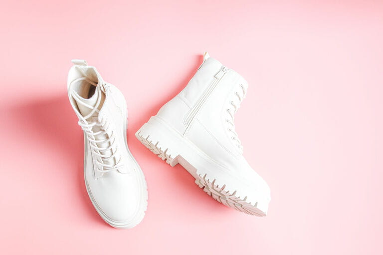 White demi-season boots made of eco-leather with screws, laces and rough sole on a pink color. White demi-season boots made of eco-leather with screws, laces and rough sole on a pink color.